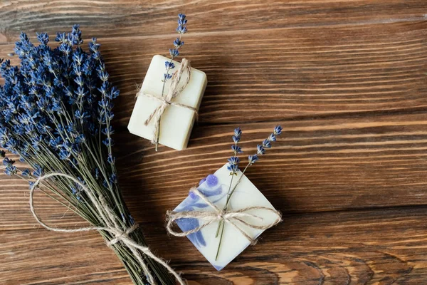 Ansicht von Lavendelblüten in der Nähe von handgemachter Seife auf Holzoberfläche — Stockfoto
