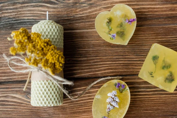 Vue du dessus des barres de savon artisanales avec des fleurs près de la bougie sur la surface en bois — Photo de stock