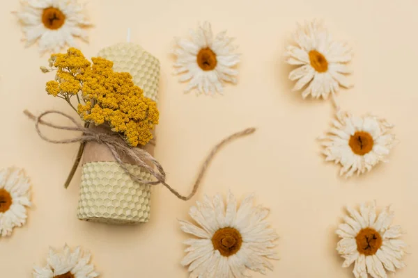 Draufsicht auf handgemachte Kerze und trockene Blumen auf beigem Hintergrund — Stockfoto