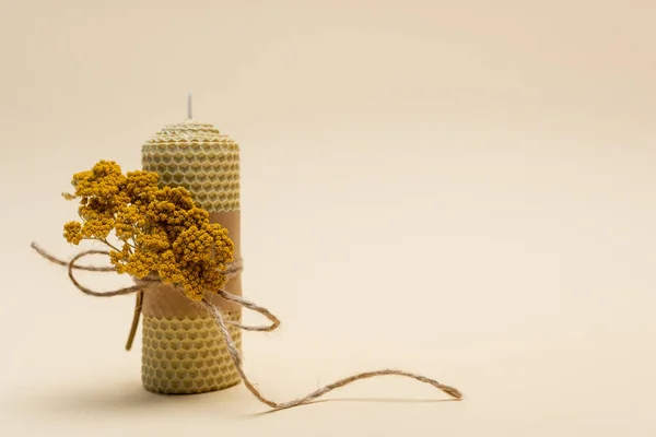 Handmade candle with dry flower and twine on beige background — Stock Photo