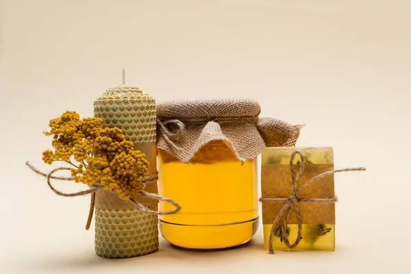 Jar of honey near handmade candle and soap on beige background — Stock Photo