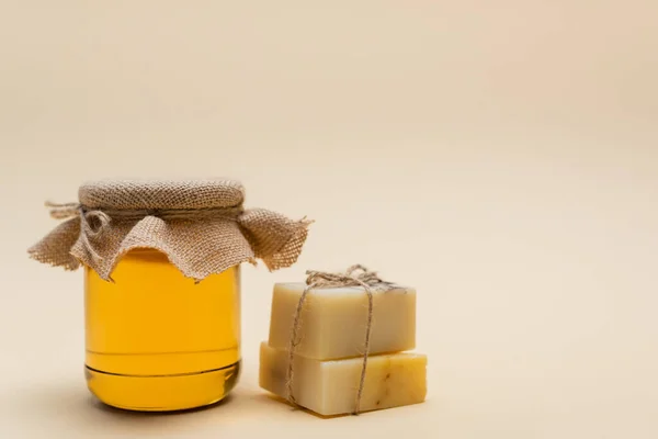 Jar with honey near handmade soap on beige background — Stock Photo