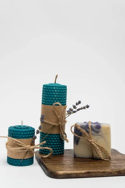 Soap bar on cutting board near candles with lavender on grey background — Stock Photo