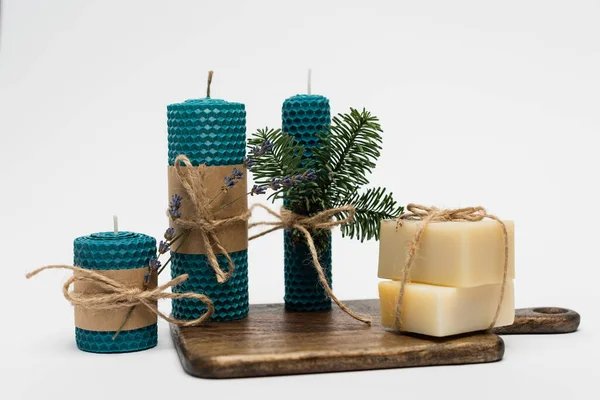 Handgefertigte Kerzen und Seife auf Schneidebrett auf grauem Hintergrund — Stockfoto