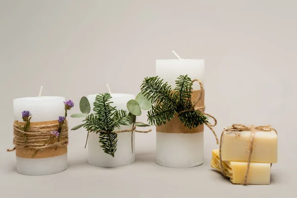 Bougies faites à la main avec des plantes près de barres de savon floues sur fond beige — Photo de stock