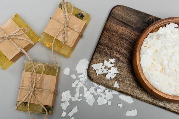 Top view of craft soap near wooden bowl and cutting board on grey background — Stock Photo