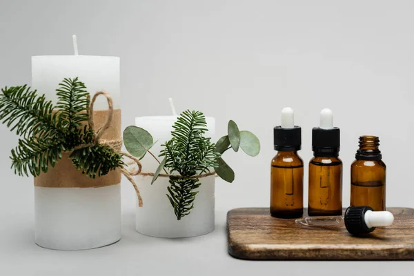 Handmade candles near essence oils on cutting board on grey background — Stock Photo