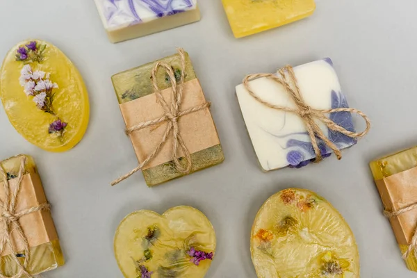 Vista dall'alto di saponette fatte a mano con fiori e spago su sfondo grigio — Foto stock