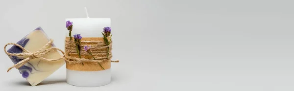 Bougie artisanale avec fleurs près du savon sur fond gris, bannière — Photo de stock