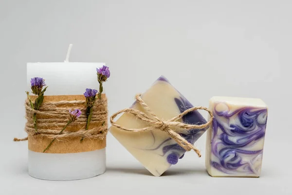 Ремесленное мыло возле свечи с цветами лаванды на сером фоне — стоковое фото