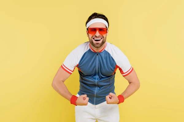 Esportista alegre mostrando músculos isolados no amarelo — Fotografia de Stock