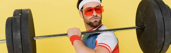 Deportista en gafas de sol mirando a la barra aislada en amarillo, bandera — Stock Photo