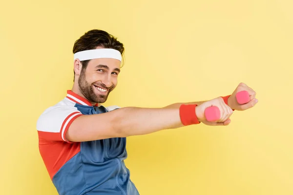 Allenamento sportivo positivo con manubri e guardando la fotocamera isolata sul giallo — Foto stock