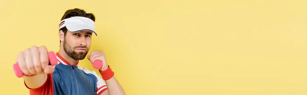 Sportsman in visor training with dumbbells isolated on yellow with copy space, banner — Stock Photo