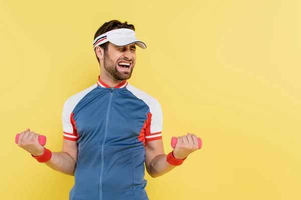 Esportista em treinamento viseira com halteres isolados em amarelo — Fotografia de Stock