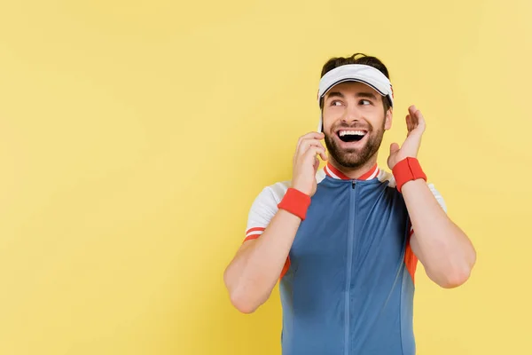 Веселий спортсмен розмовляє на смартфоні ізольовано на жовтому — стокове фото