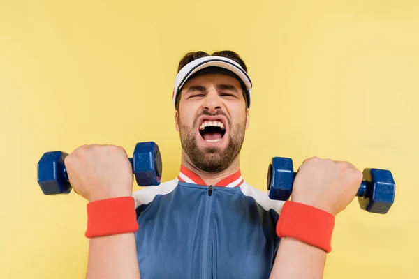 Giovane sportivo che lavora con i manubri isolati sul giallo — Foto stock