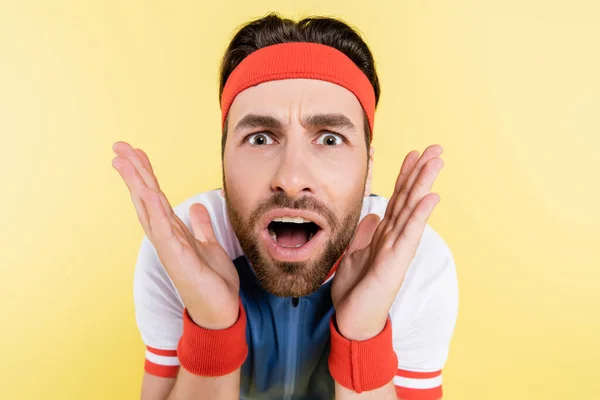 Portrait of shocked sportsman looking at camera isolated on yellow — Stock Photo