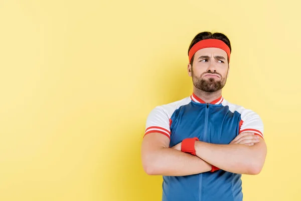 Pensive sportsman crossing arms isolated on yellow — Stock Photo