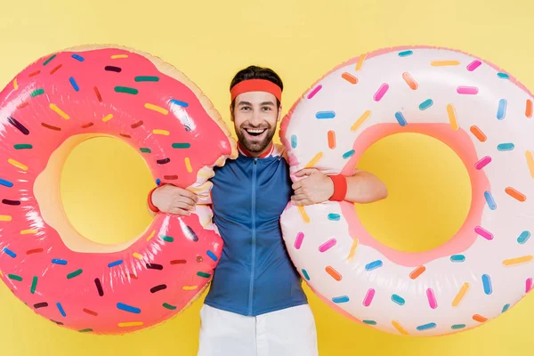 Smiling sportsman holding swim rings isolated on yellow — Stock Photo