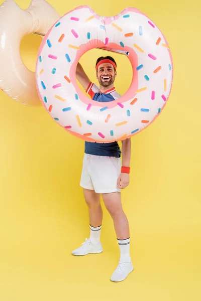 Volle Länge des positiven Sportlers hält Schwimmringe auf gelbem Hintergrund — Stockfoto