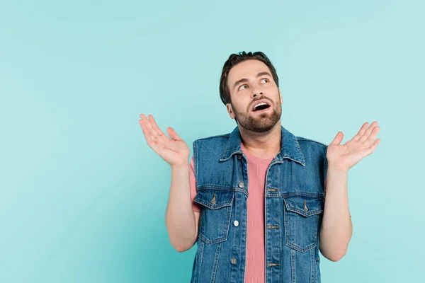 Shocked man in denim vest looking away isolated on blue — Stock Photo