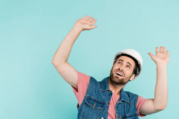 Scared man in hardhat looking up isolated on blue — Stock Photo