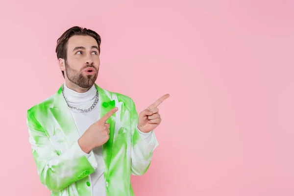 Geschockter Mann in Jacke zeigt mit Fingern auf rosa — Stockfoto