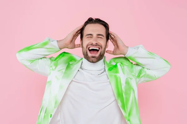 Hombre gritando en chaqueta tocando la cabeza aislado en rosa - foto de stock