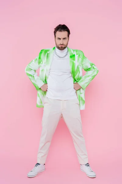 Full length of serious man looking at camera on pink background — Stock Photo