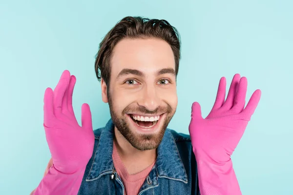 Hombre positivo en guantes de goma mirando a la cámara aislada en azul - foto de stock