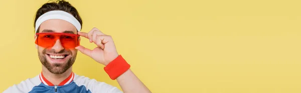 Sportif gai dans des lunettes de soleil regardant la caméra isolée sur jaune avec espace de copie, bannière — Photo de stock