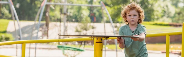 Curly boy on carousel looking at camera, banner — Stock Photo