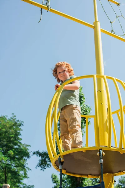 Vista de ángulo bajo del niño mirando la cámara desde la torre alta en el parque de atracciones - foto de stock