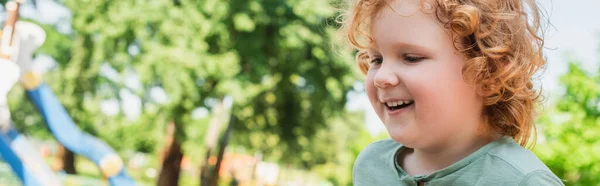 Ritratto di ragazzo rosso con i capelli ricci sorridenti all'aperto, striscione — Foto stock