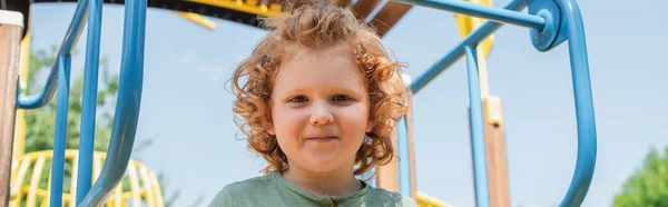 Niño alegre mirando la cámara mientras juega al aire libre, pancarta - foto de stock