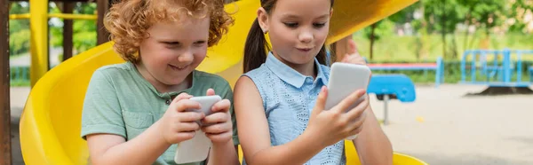 Happy kids playing on smartphones on playground, banner — Stock Photo