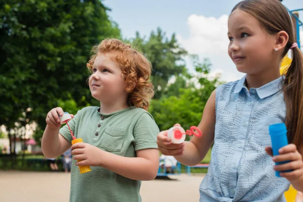 Kids holding bubble blowers while spending time outdoors — Stock Photo