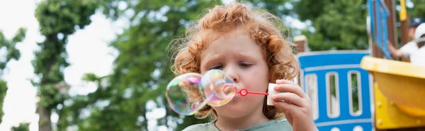 Garçon soufflant des bulles de savon à l'extérieur dans le parc, bannière — Photo de stock