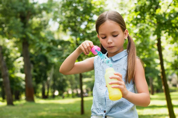 Chica en mangas blusa celebración burbuja ventilador en parque - foto de stock