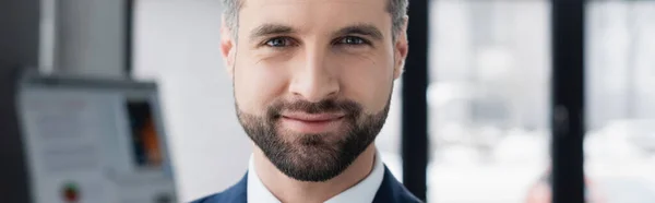 Retrato de economista barbudo feliz sonriendo a la cámara en la oficina borrosa, pancarta - foto de stock