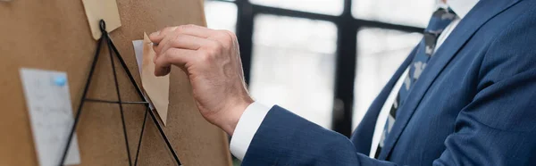 Abgeschnittene Ansicht des Ökonomen, der klebrige Zettel auf Korkplatte heftet, Banner — Stockfoto