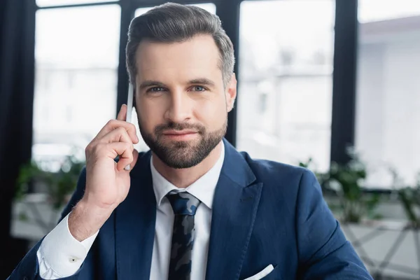 Brunette economist in blazer and tie calling on mobile phone and looking at camera — стоковое фото