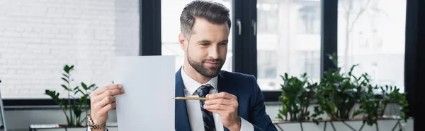 Brünetter Geschäftsmann zeigt mit Bleistift auf leeres Papier, Banner — Stockfoto