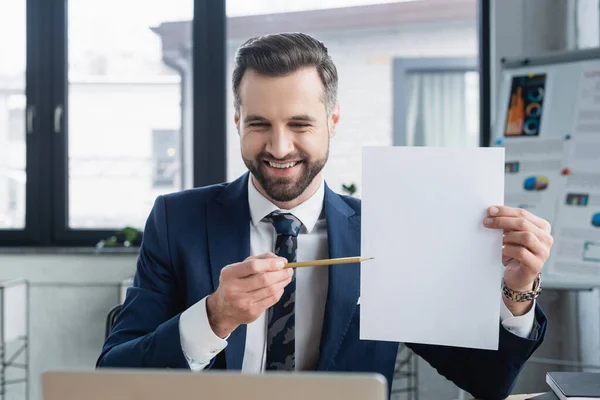 Lächelnder Ökonom zeigt mit Bleistift auf leeres Papier im Büro — Stockfoto