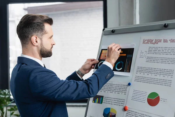 Seitenansicht des Ökonomen, der Analytik auf Flipchart im Büro platziert — Stockfoto