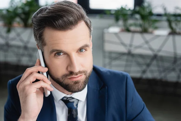Brunette economist looking at camera while calling on smartphone in office — Stock Photo