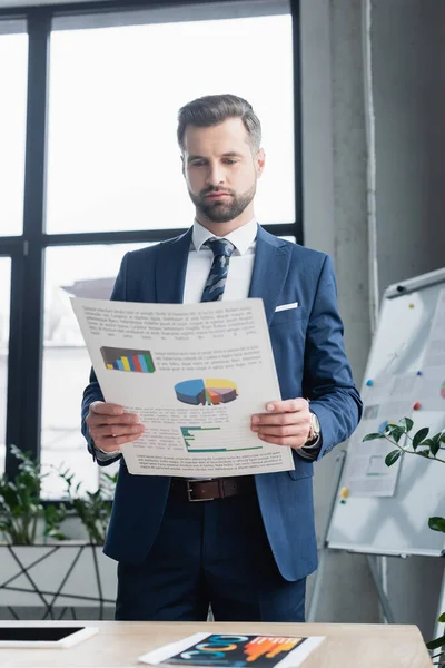 Brunette economist looking at document with analytics in office — Stock Photo