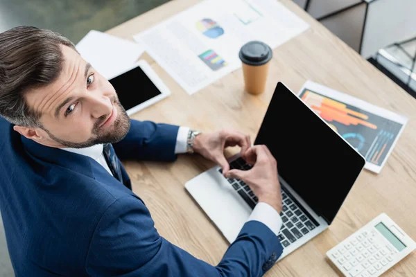 Vue aérienne de l'économiste heureux montrant signe cardiaque près d'un ordinateur portable avec écran vide — Photo de stock