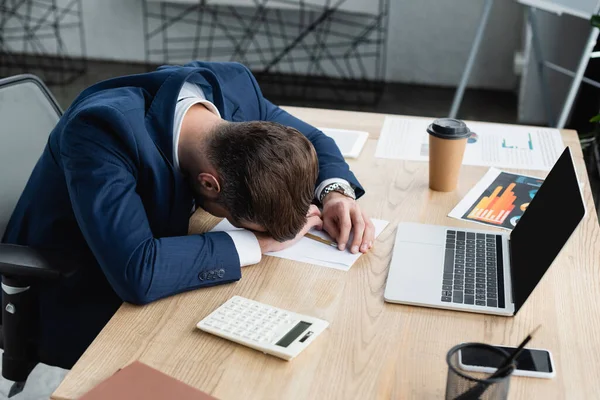 Economista cansado dormindo no local de trabalho perto calculadora e laptop com tela em branco — Fotografia de Stock